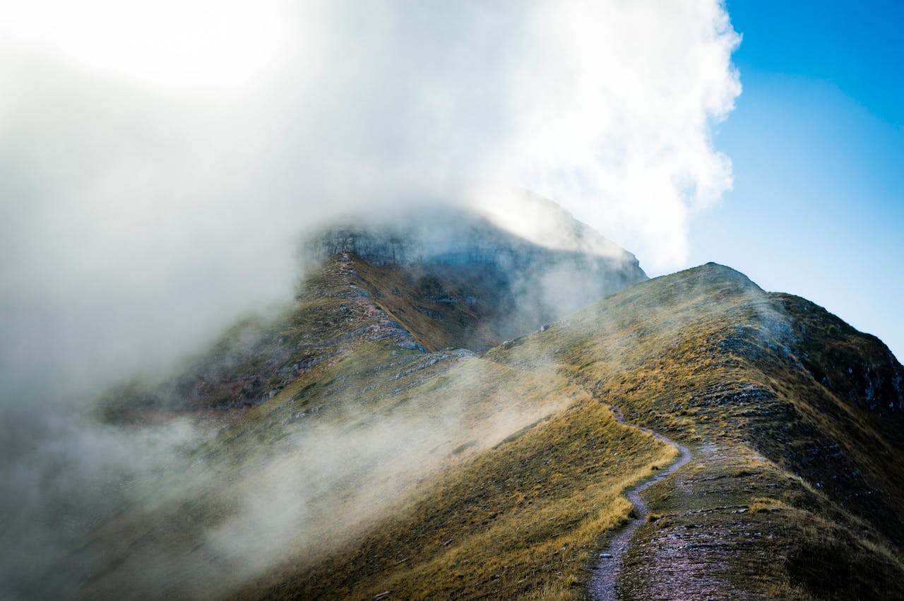 Explore the serene misty mountain landscape in Montemonaco, Italy, with a winding path and scenic views.